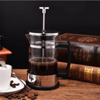 French press with coffee on a wooden table with books in the background