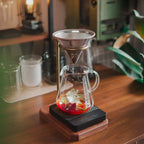 Tea-making setup with glass teapot and filter on a wooden surface